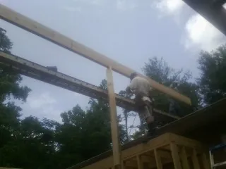Carpenter setting a ridge beam over a new addition frame — Ice Dam Removal by Roofing Brothers in Gerber