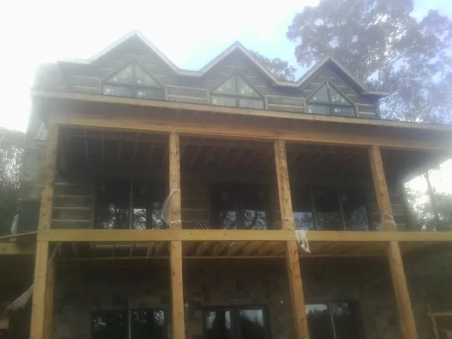 Dormers and porch framing on a large log home under construction — Roof Coating work by our crew in Gerber