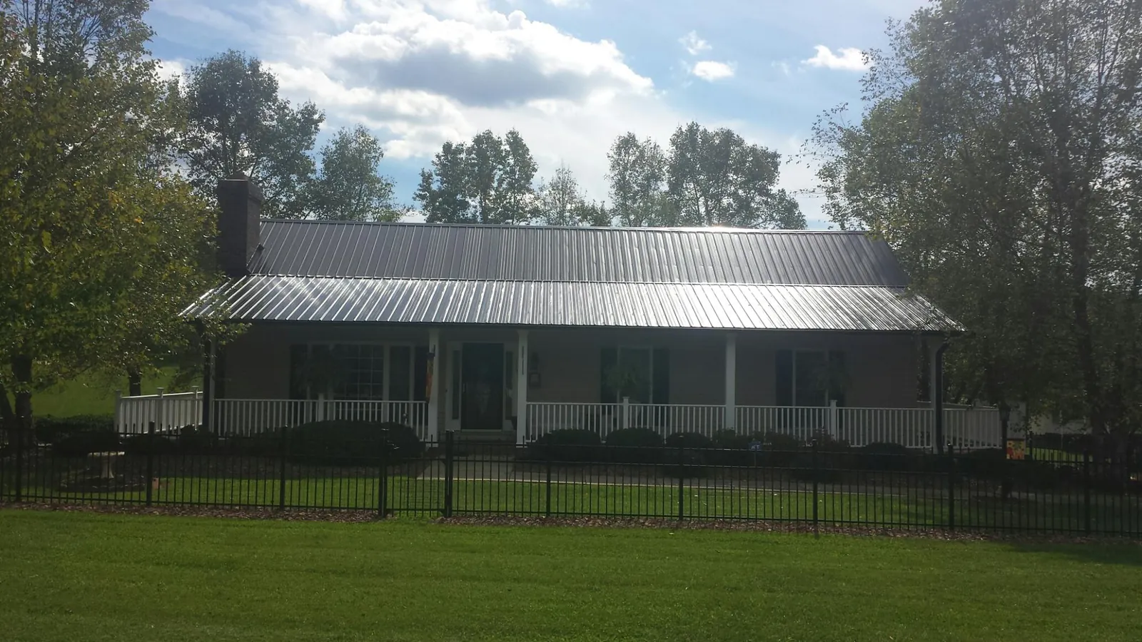 Gray metal roof on a brick ranch with a full width front porch — Gutter Guard Installation work by our crew in Gerber