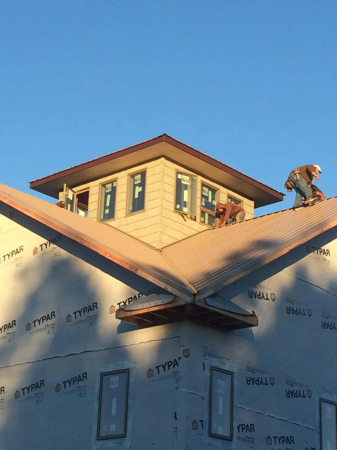 Roofers working around a rooftop cupola on a new metal roof at sunset — Roof Waterproofing in Gerber by Roofing Brothers
